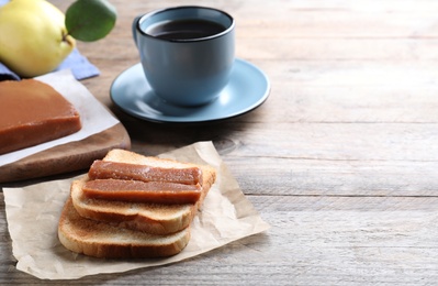 Photo of Tasty sandwich with quince paste served for breakfast on wooden table, space for text