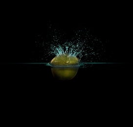 Apple falling down into clear water against black background