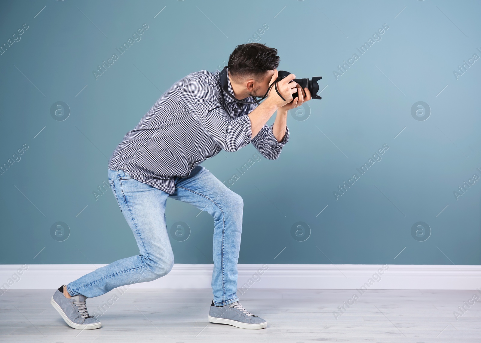 Photo of Male photographer with camera near grey wall