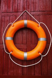 Photo of Orange life buoy hanging on red wooden wall