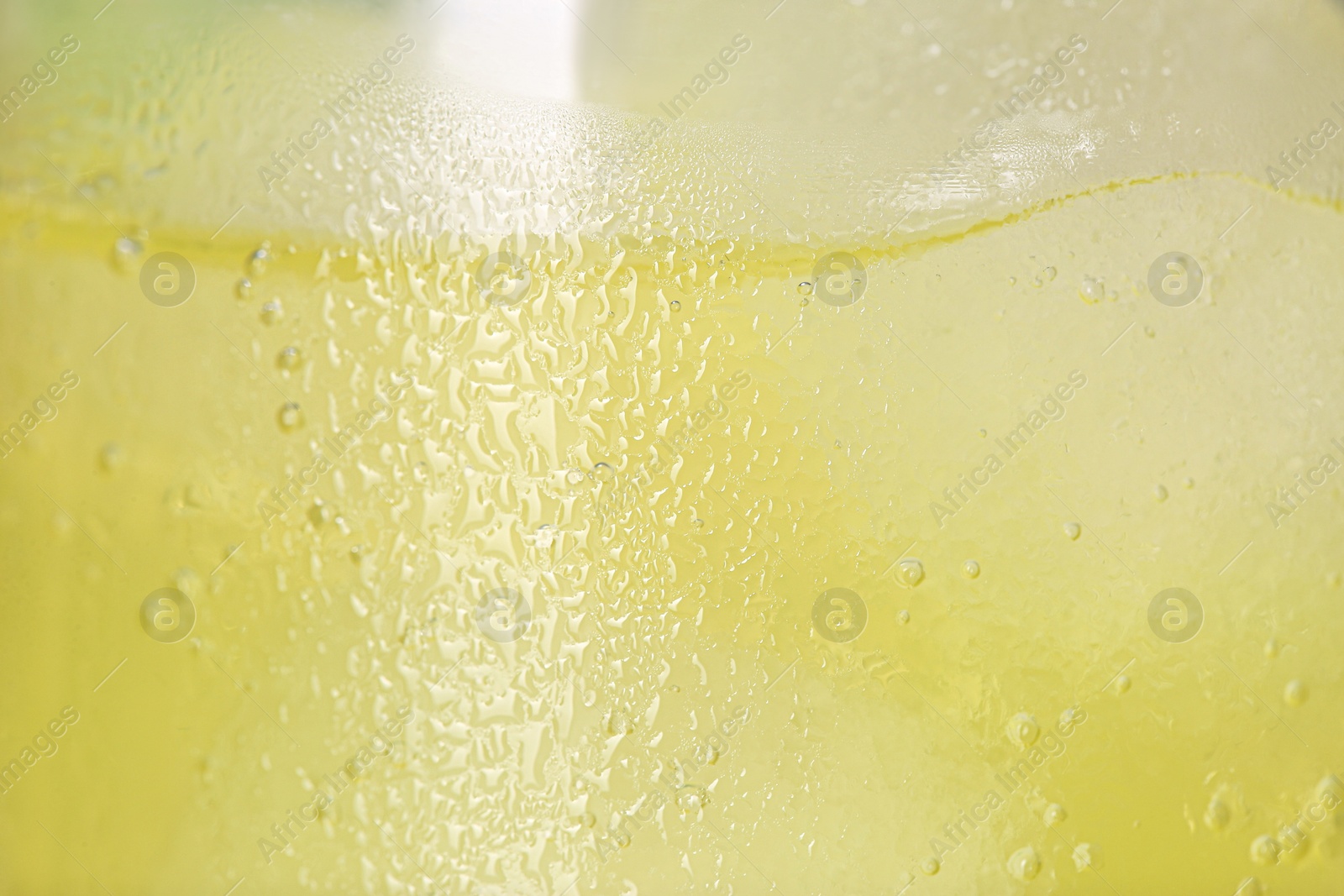 Photo of Glass of refreshing drink with ice cubes as background, closeup