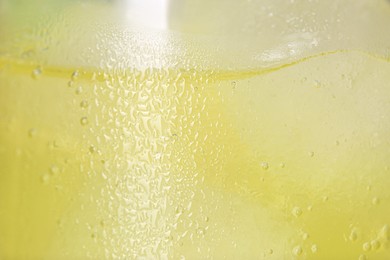 Glass of refreshing drink with ice cubes as background, closeup