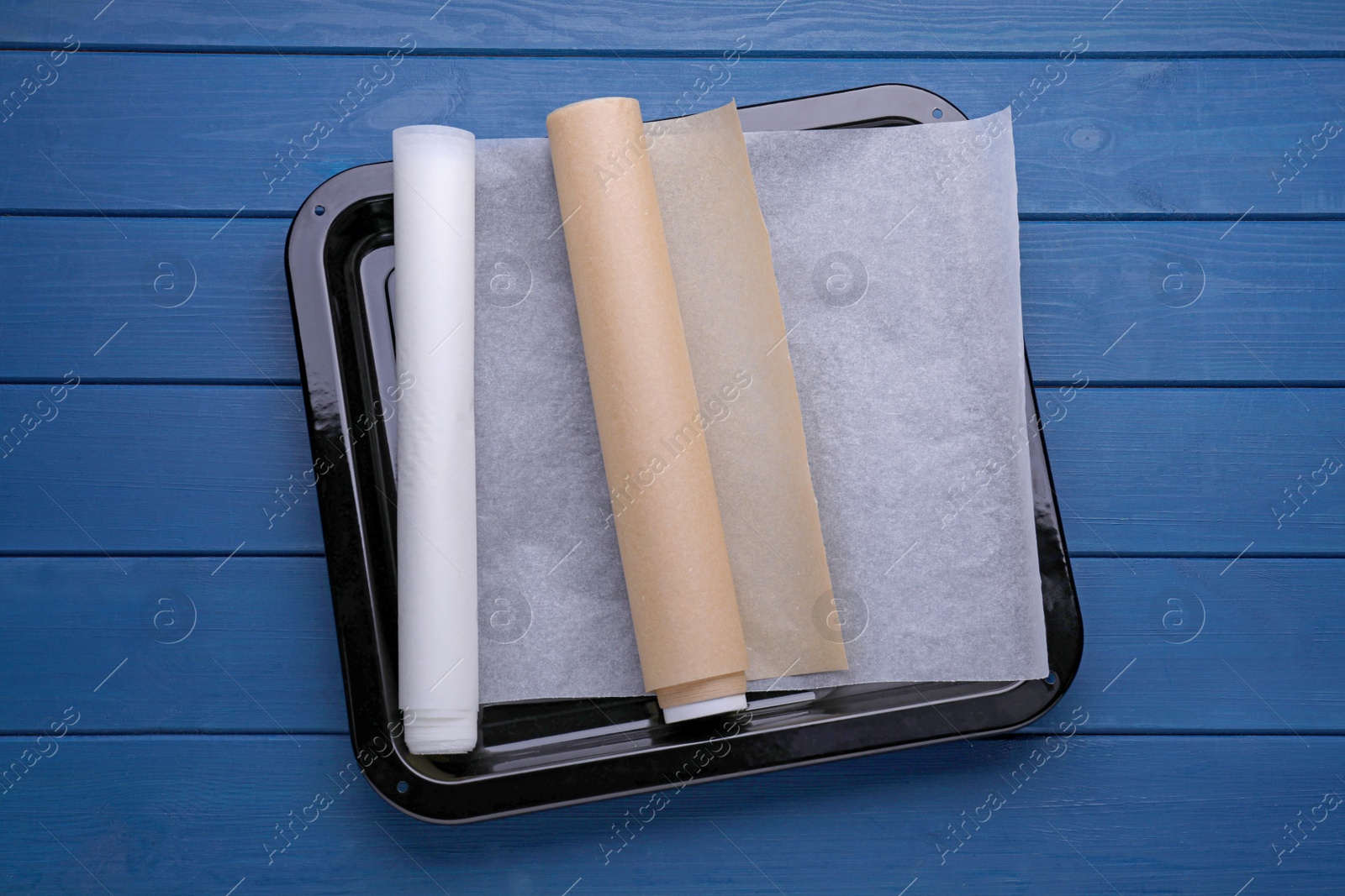 Photo of Rolls of baking parchment paper on blue wooden table, top view