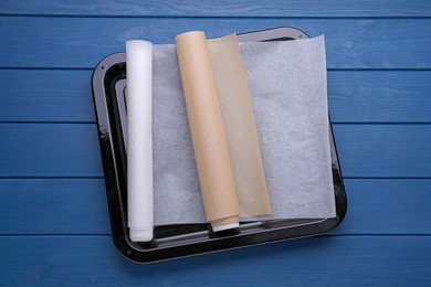 Photo of Rolls of baking parchment paper on blue wooden table, top view