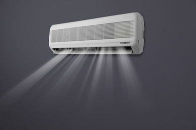 Modern air conditioner on black wall indoors