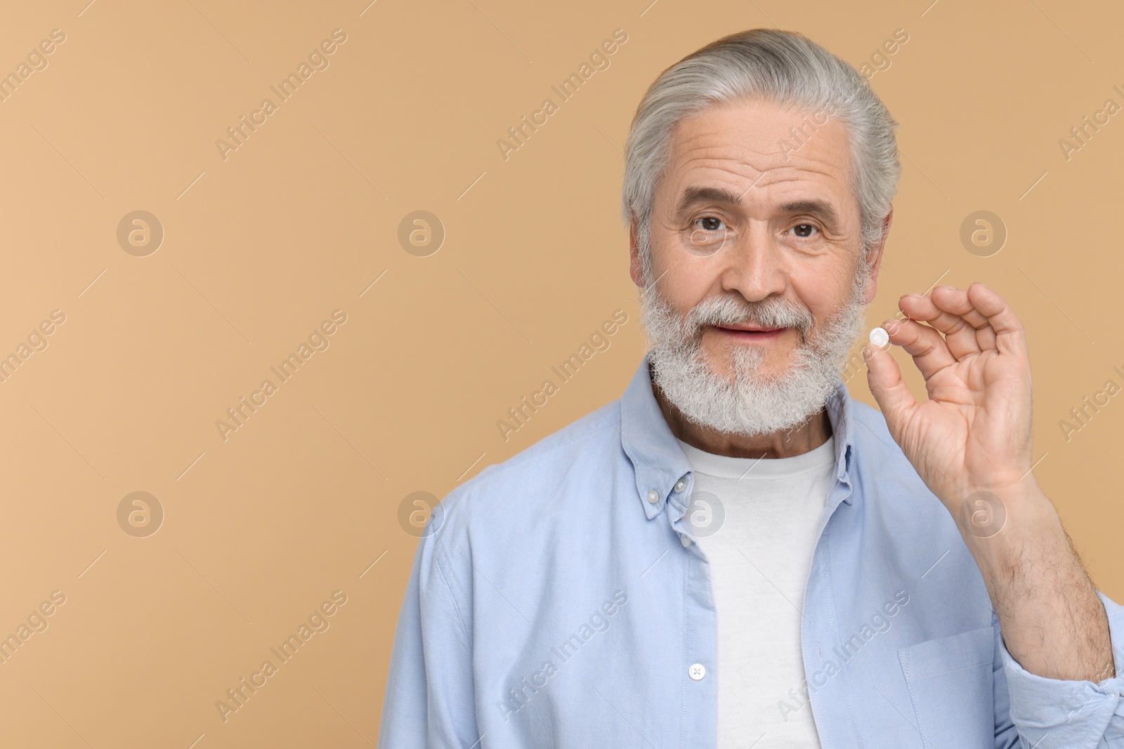 Photo of Senior man with pill on beige background. Space for text