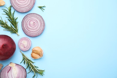 Photo of Fresh red onions, garlic and rosemary on light blue background, flat lay. Space for text