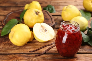 Photo of Delicious quince jam and fruits with vanilla on wooden table, closeup