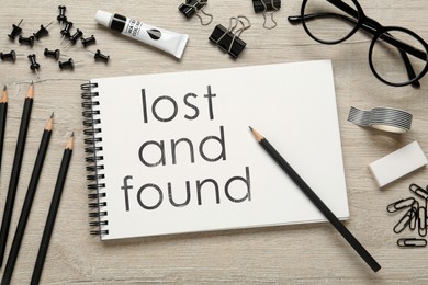 Image of Flat lay composition of sketchbook with phrase Lost and Found on wooden table