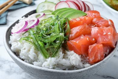 Delicious poke bowl with salmon and vegetables on table, closeup