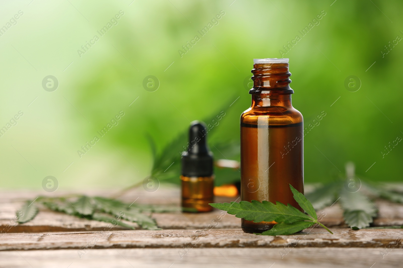 Photo of Bottle with hemp extract on table and space for text against blurred background