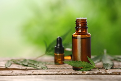 Bottle with hemp extract on table and space for text against blurred background