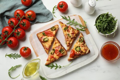 Photo of Tasty pizza toasts and ingredients on white marble table, flat lay