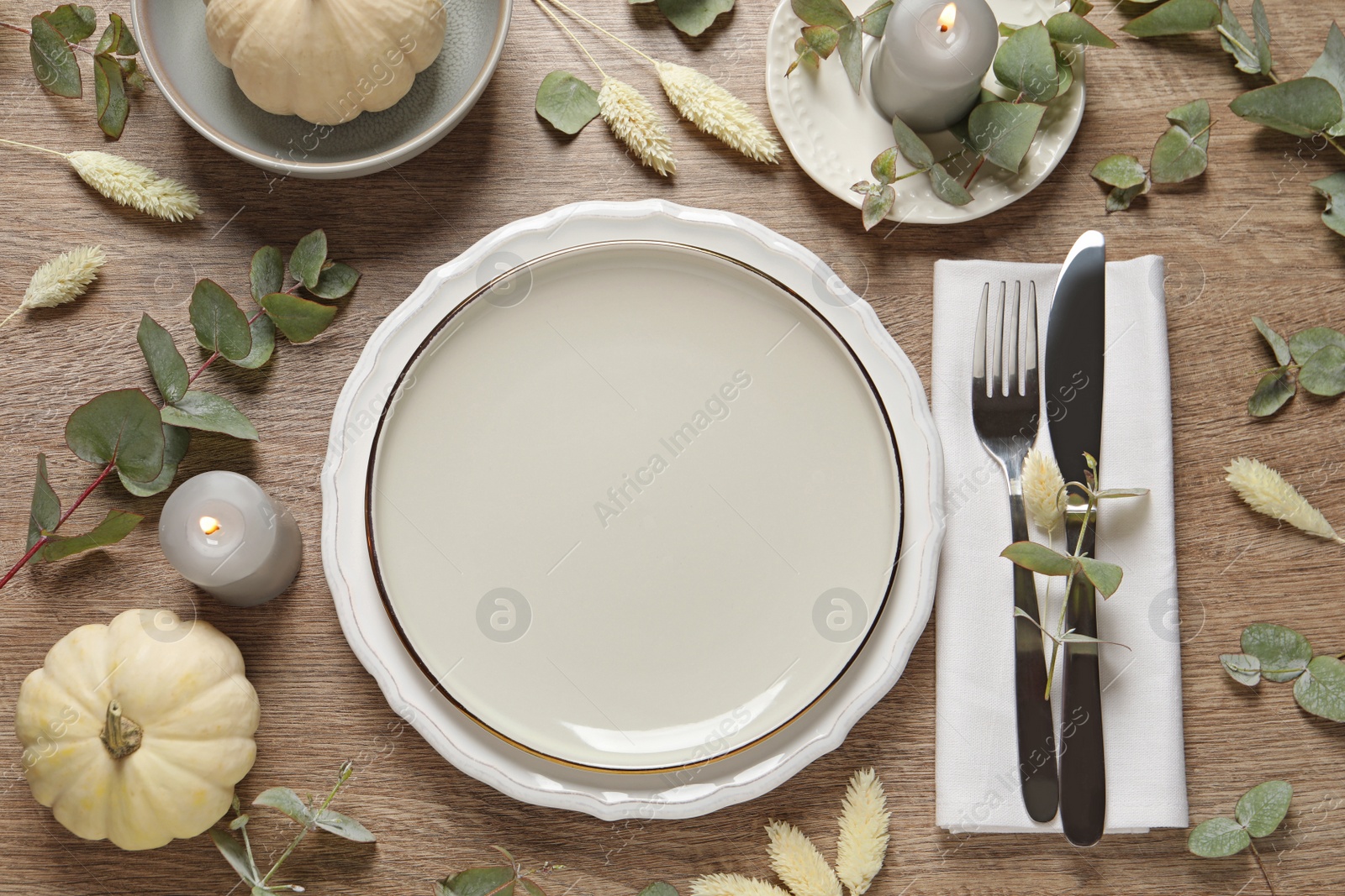 Photo of Festive table setting with floral decor and pumpkins on wooden background, flat lay