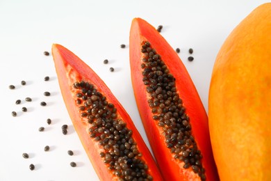 Fresh juicy cut and whole papaya fruits on white background, flat lay