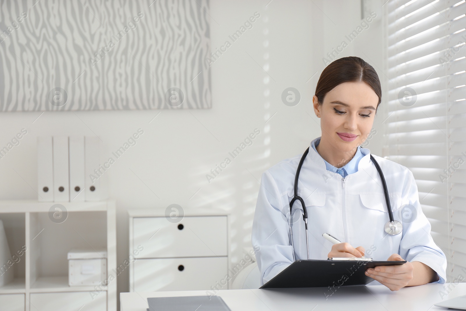 Photo of Young female doctor working at table in office