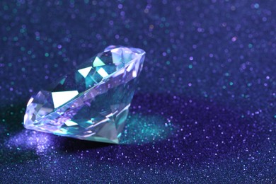 Photo of Beautiful shiny diamond on blue glitter background, closeup. Space for text