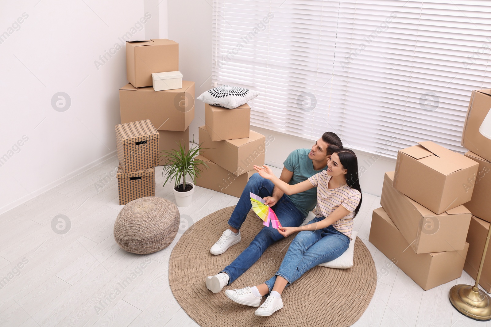 Photo of Happy couple with color palette samples in their new flat on moving day, above view