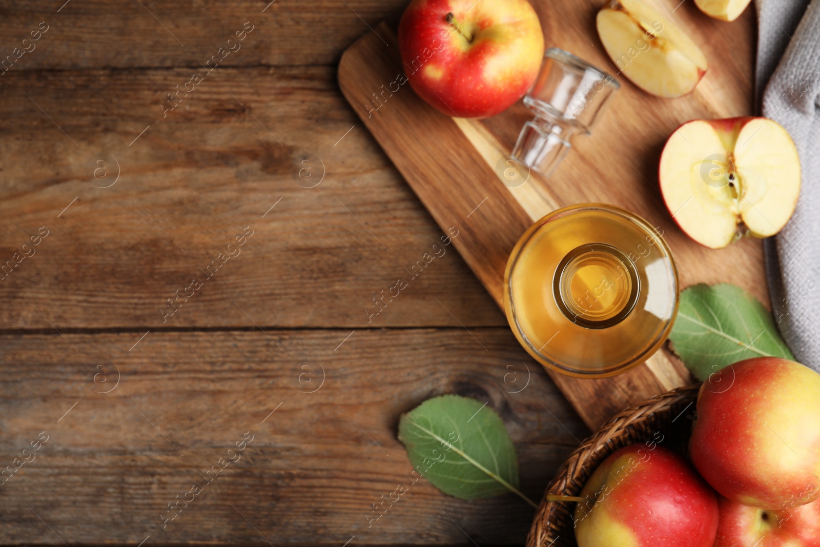 Photo of Natural apple vinegar and fresh fruits on wooden table, flat lay. Space for text