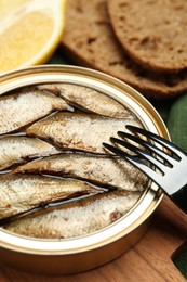 Photo of Canned sprats and fork on board, closeup