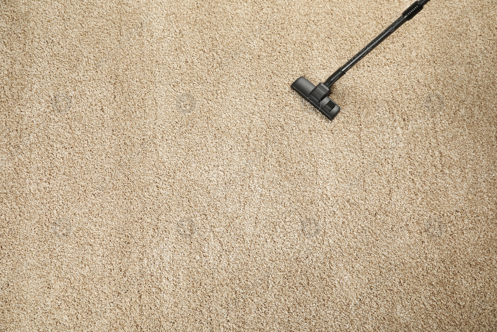 Photo of Removing dirt from beige carpet with modern vacuum cleaner, top view. Space for text