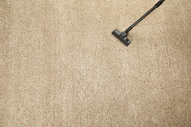 Photo of Removing dirt from beige carpet with modern vacuum cleaner, top view. Space for text