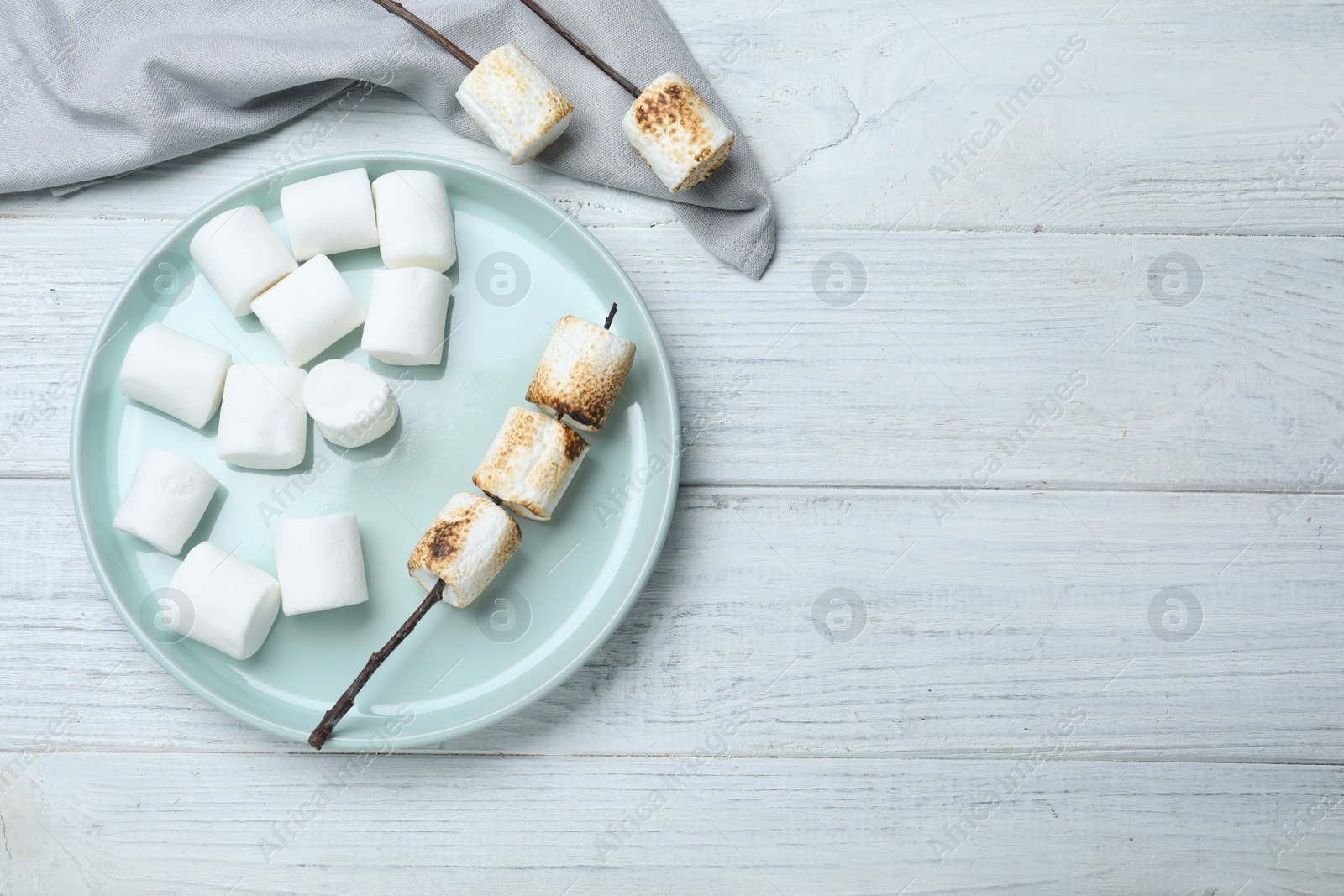 Photo of Fresh and roasted marshmallows on white wooden table, flat lay. Space for text