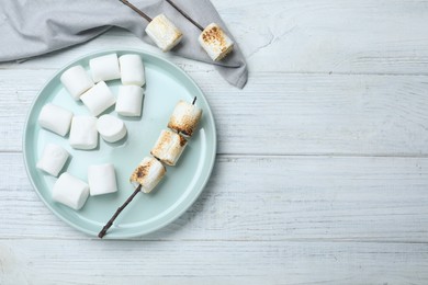 Fresh and roasted marshmallows on white wooden table, flat lay. Space for text