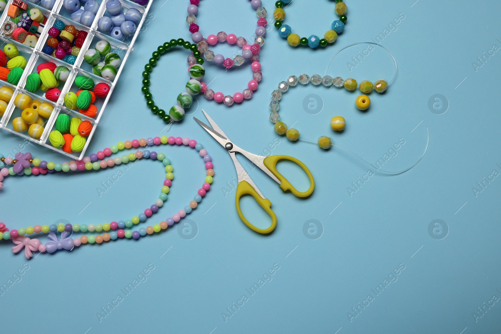 Photo of Flat lay composition with different colorful beads on light blue background, space for text