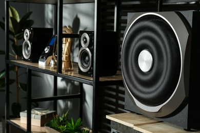 Photo of Modern powerful audio speaker system on shelving indoors