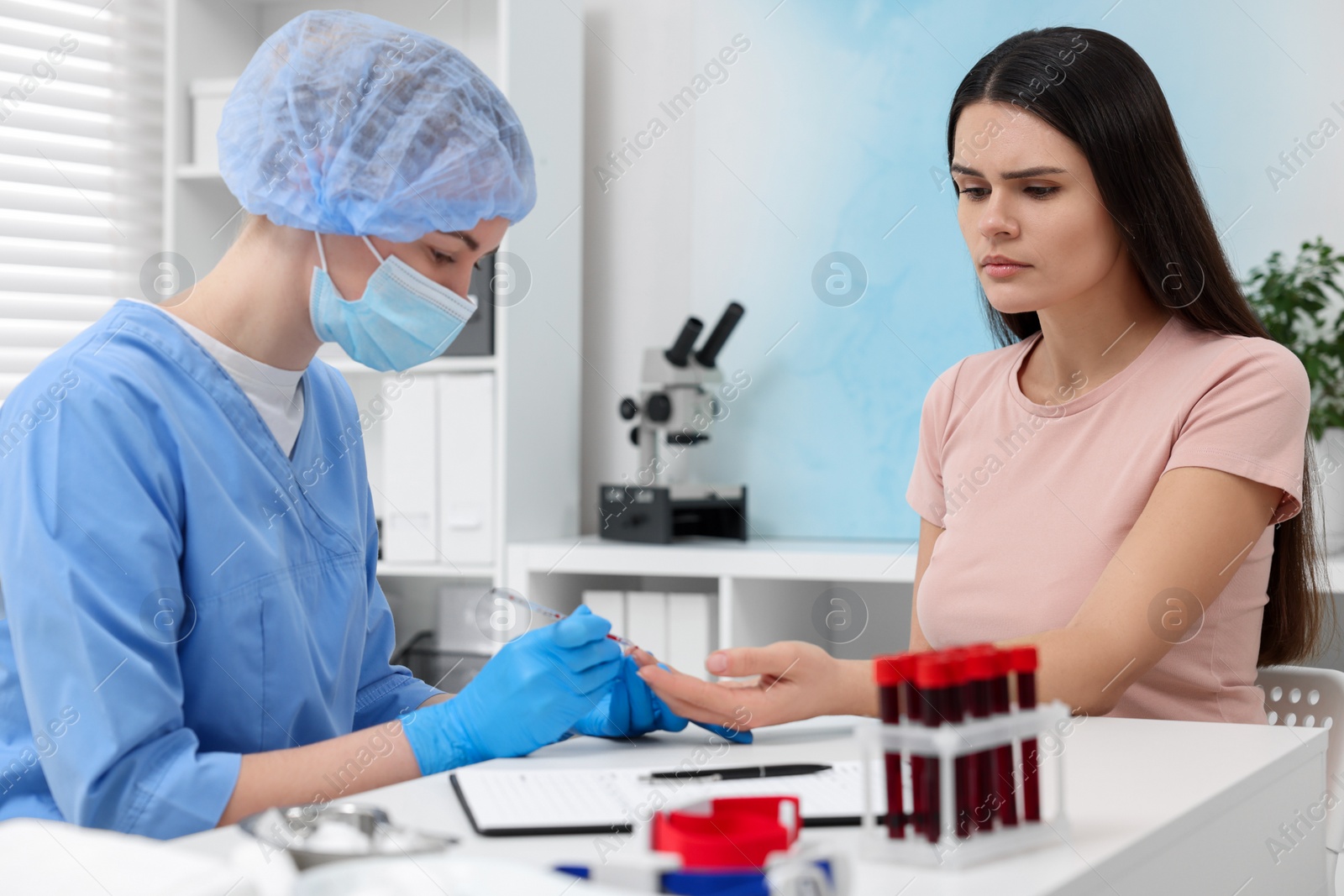 Photo of Laboratory testing. Doctor taking blood sample from patient at white table in hospital