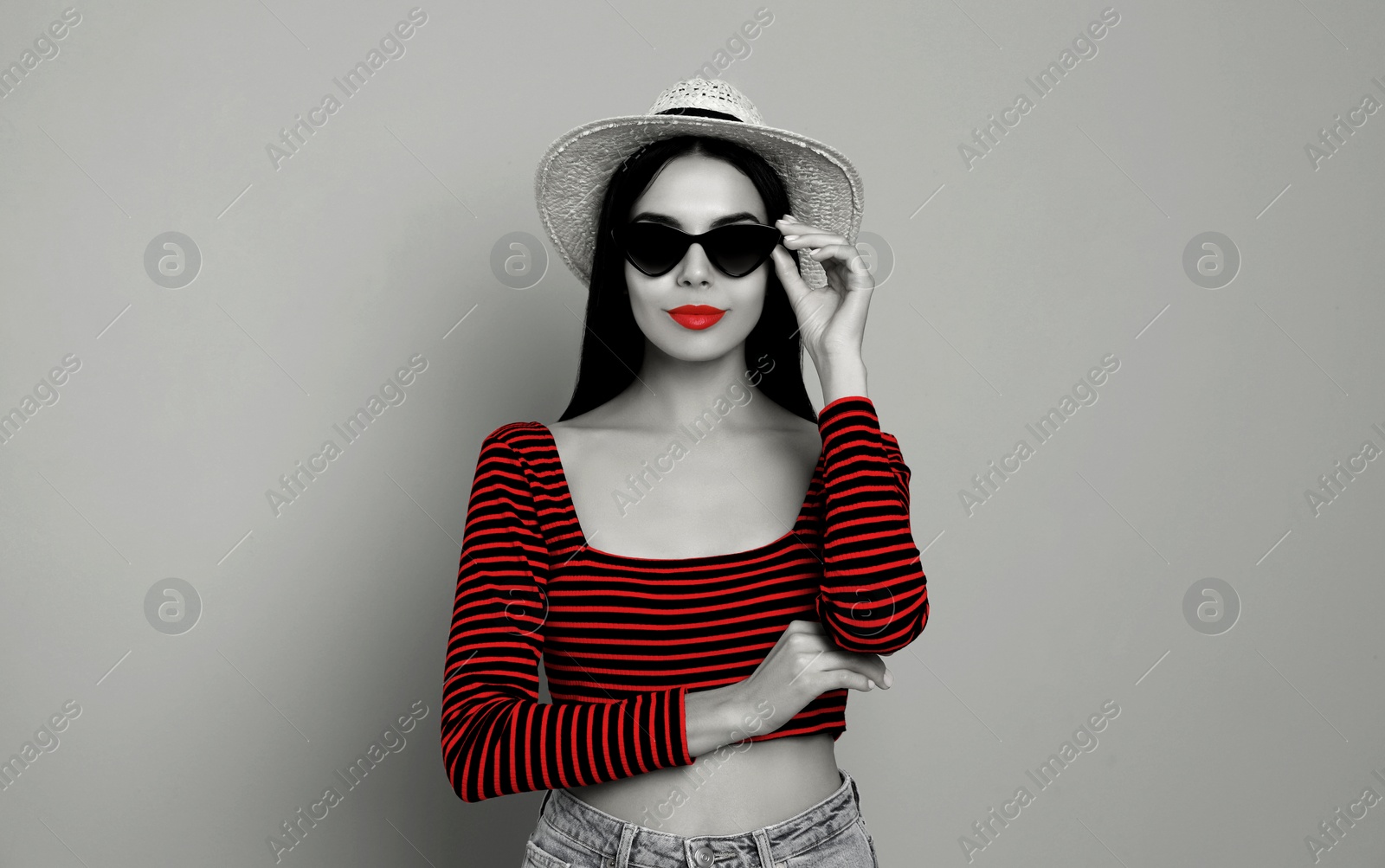 Image of Attractive woman in stylish sunglasses on light grey background. Black and white photo with red accent