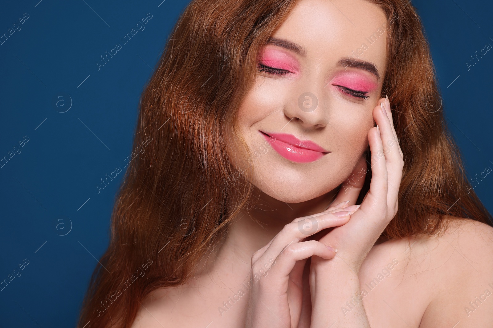 Photo of Portrait of beautiful young woman with makeup posing on blue background