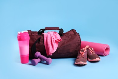 Photo of Red bag and sports accessories on light blue background