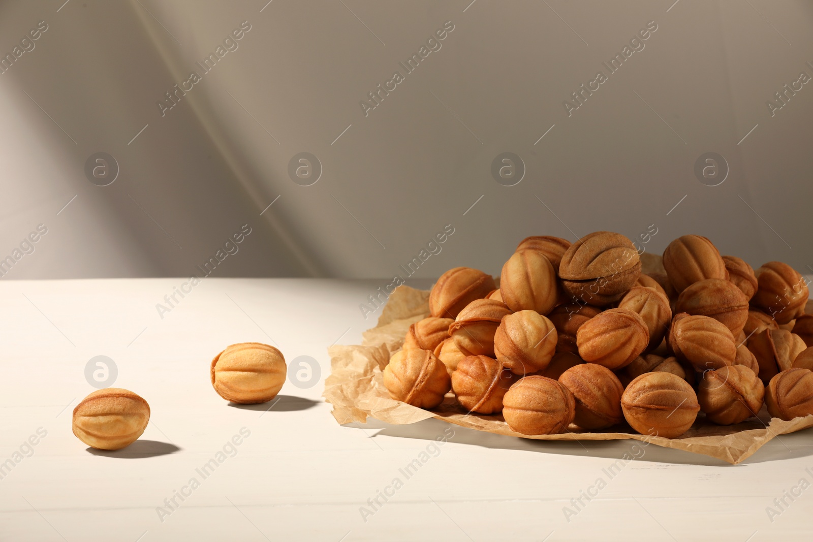 Photo of Freshly baked walnut shaped cookies on white wooden table, space for text. Homemade pastry filled with caramelized condensed milk