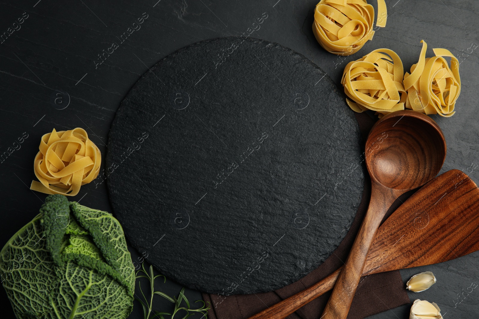 Photo of Slate plate surrounded by different ingredients on black table, flat lay with space for text. Cooking classes