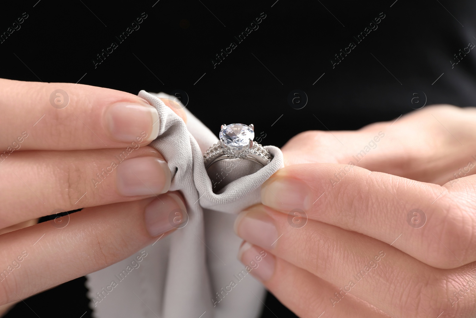 Photo of Jeweler cleaning diamond ring with microfiber cloth, closeup