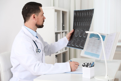 Orthopedist examining X-ray picture at desk in clinic