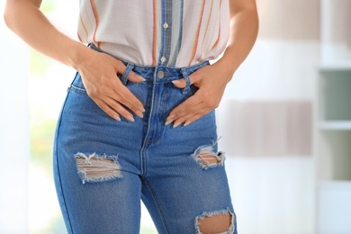 Photo of Young woman in stylish blue jeans indoors