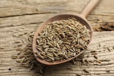 Photo of Spoon with caraway seeds on wooden table, closeup