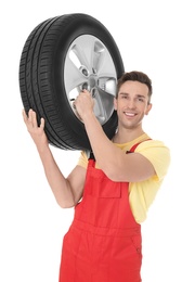 Photo of Young mechanic in uniform holding car tire on white background