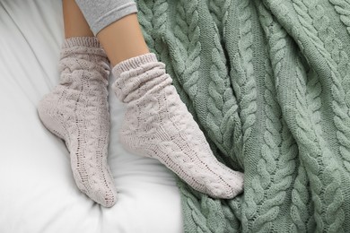 Photo of Woman wearing warm socks in comfortable bed, above view. Space for text