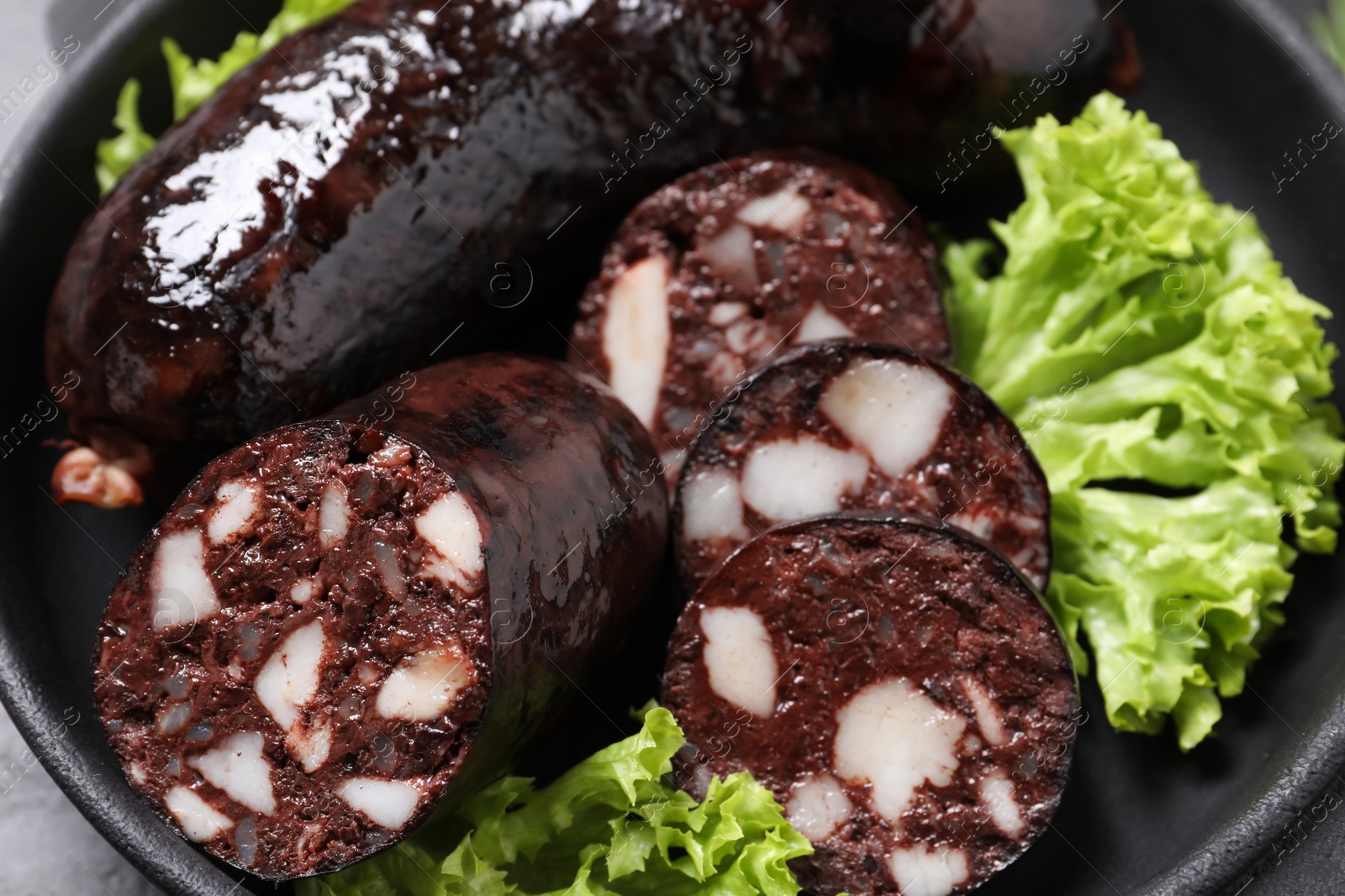 Photo of Tasty blood sausages with lettuce in pan, closeup