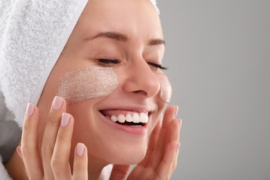Photo of Woman applying cosmetic product onto her face against grey background, closeup with space for text. Spa treatments