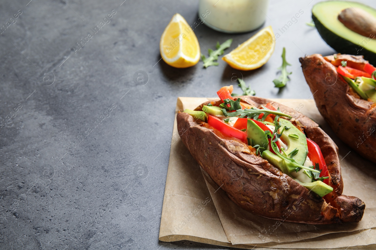 Photo of Stuffed sweet potato served on grey table. Space for text