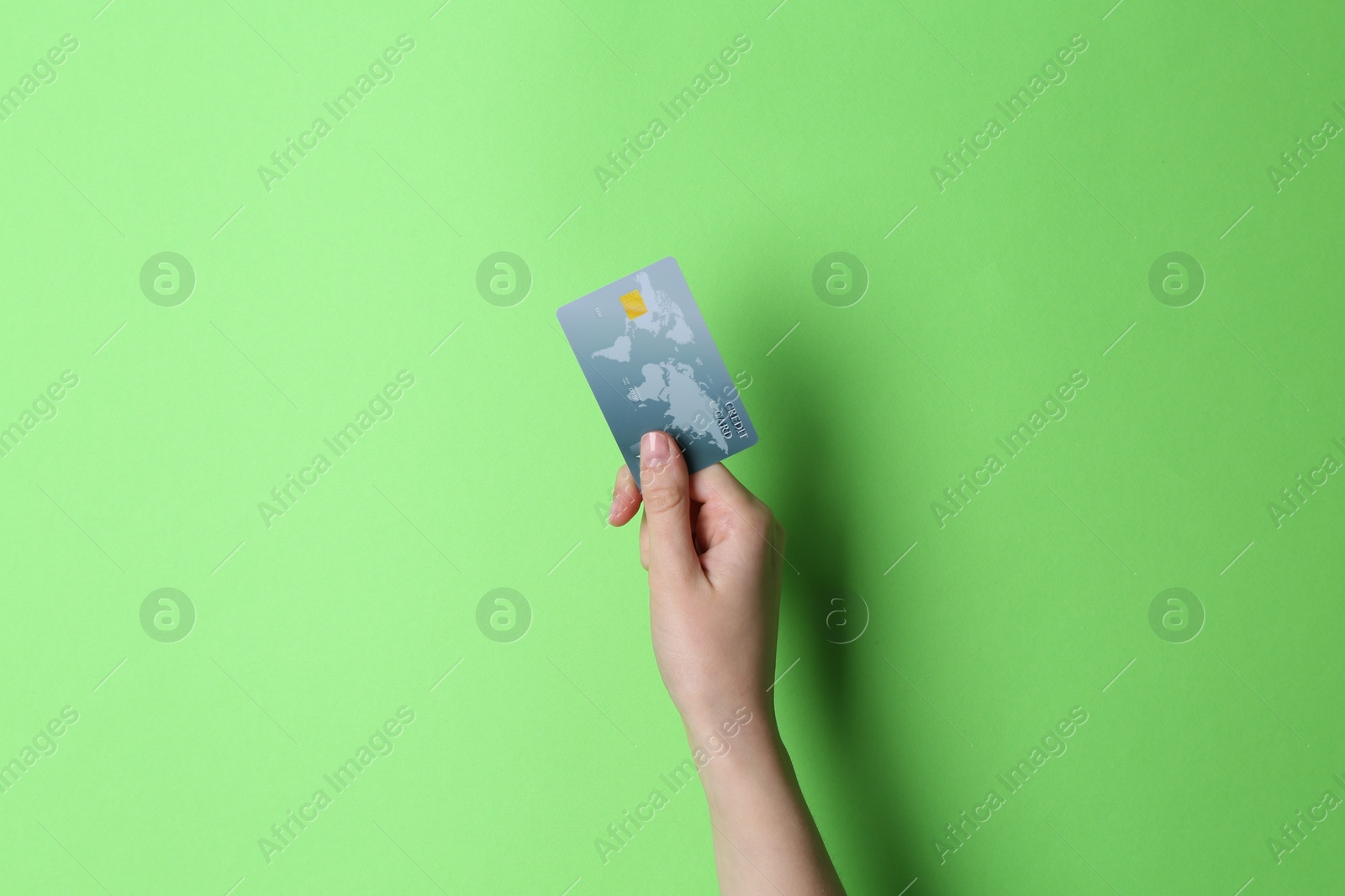 Photo of Woman holding credit card on light green background, closeup