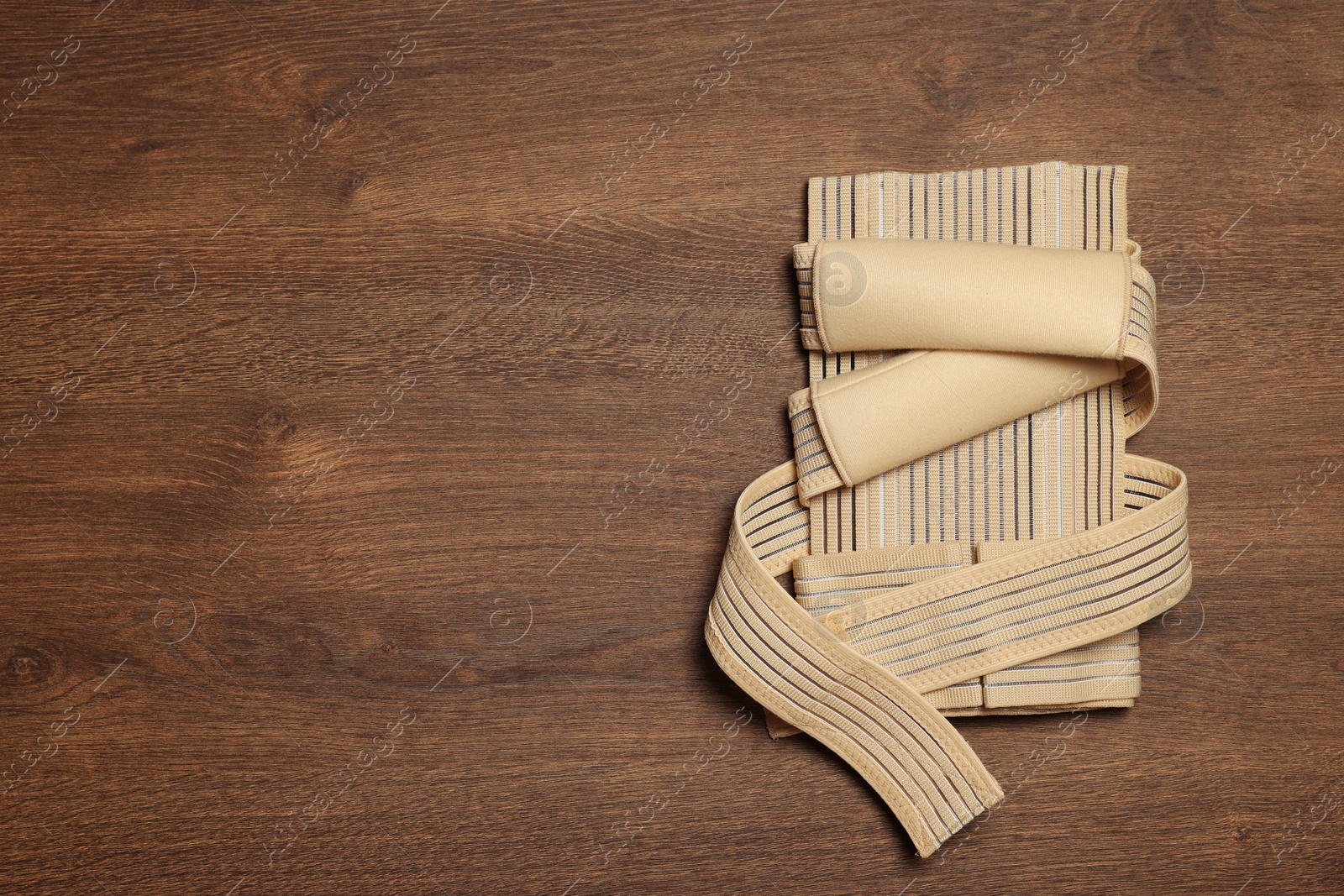 Photo of Beige posture corrector on wooden table, top view. Space for text