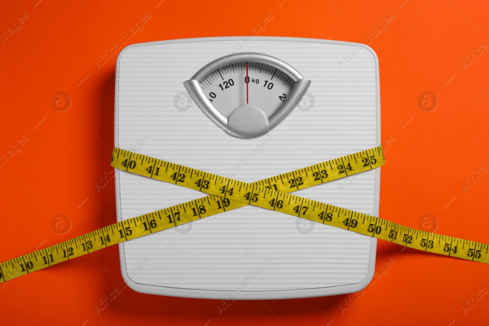 Photo of Scales and measuring tape on orange background, top view. Weight loss concept