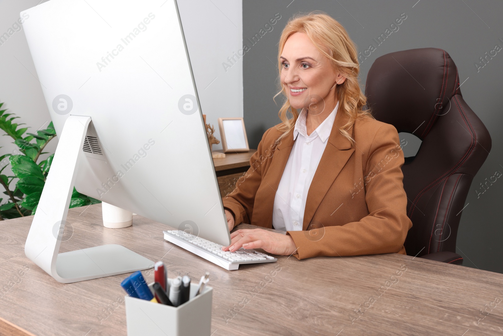 Photo of Lady boss working on computer at desk in office. Successful businesswoman