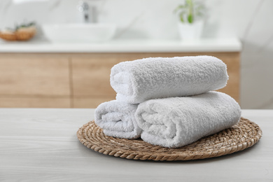 Photo of Rolled fresh towels on white table in bathroom